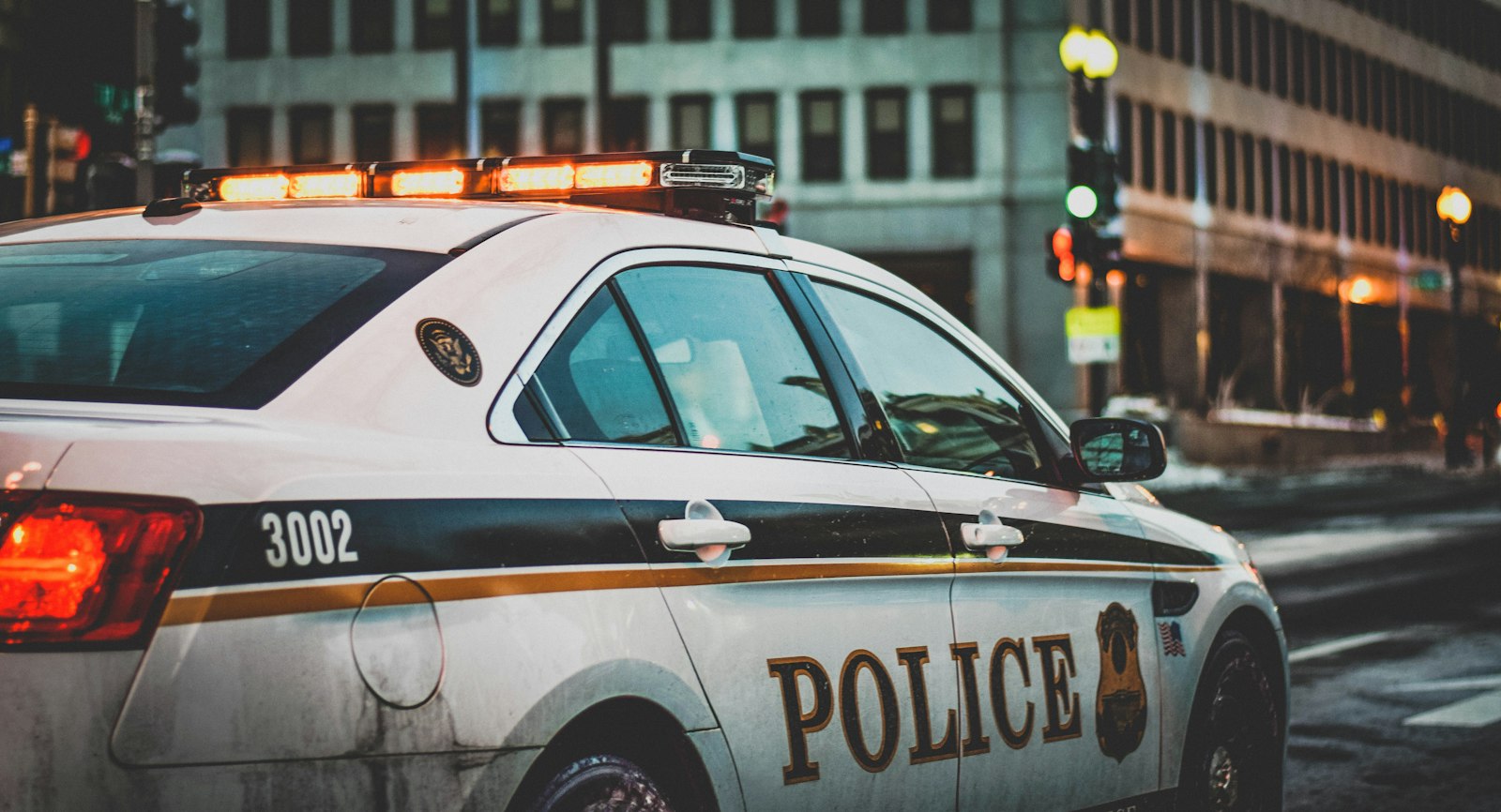 A Philadelphia-style police patrol car with lights on parked on a city street at dusk