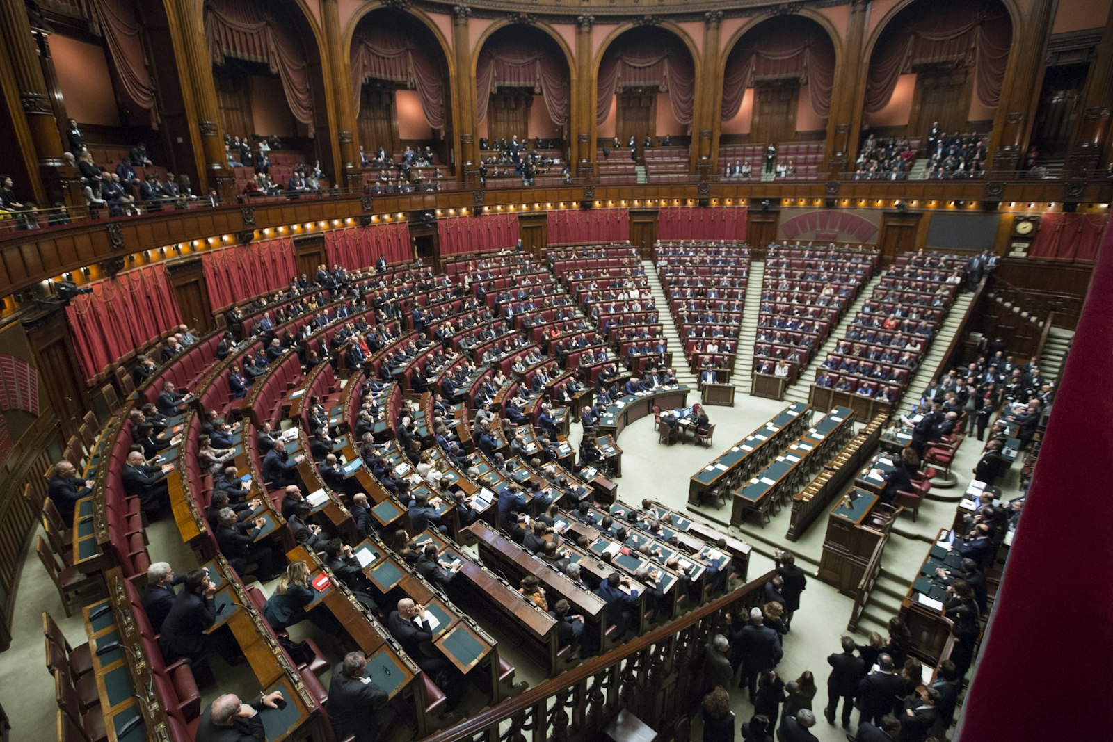 A wide view of a legislative chamber with rows of seated members under a vaulted ceiling