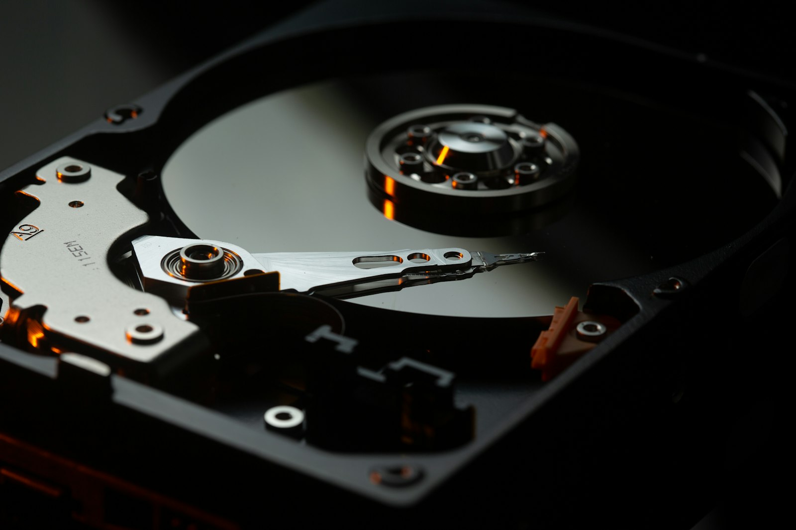 An open hard disk drive showing the platter and read head on a dark background