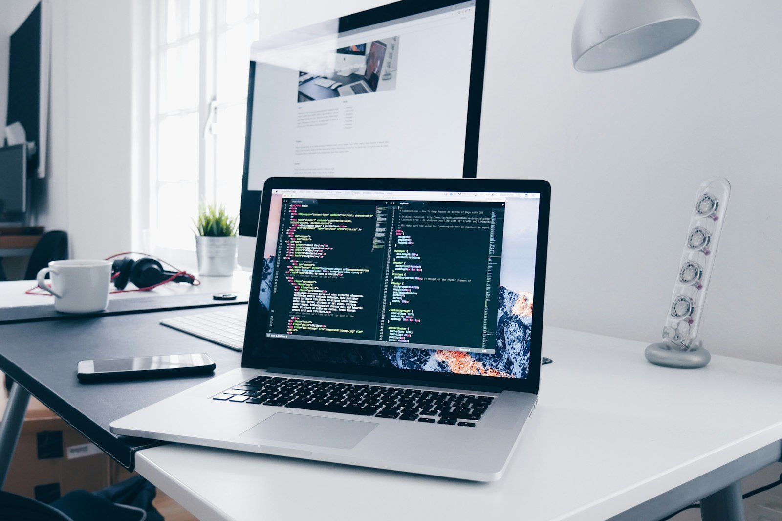Developer laptop workstation showing code on screen and workspace setup.